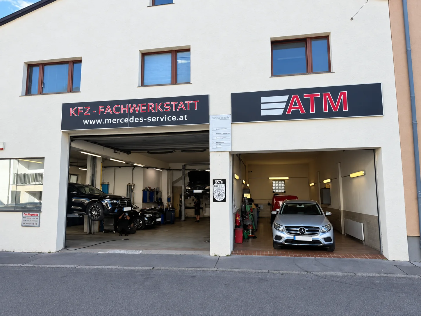 Außenansicht der ATM-Fachwerkstatt mit Beschilderung und beiden Einfahrten